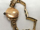 an image of a close up of a gold watch on a white surface