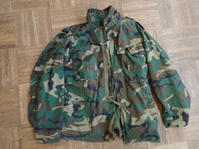camouflage jacket sitting on a wooden floor on a hard wood floor