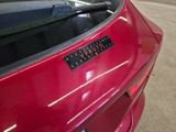 a close up of a red car with a sticker on it