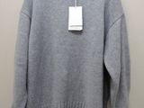 a gray sweater hanging on a hanger on a wall