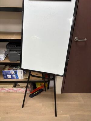 un tableau blanc posé sur un trépied dans une pièce