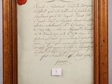 a framed photograph of a piece of paper with a red wax stamp on it