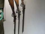 three old guns are displayed on a wall in a room