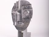a metal sculpture of a man ' s face on a white surface