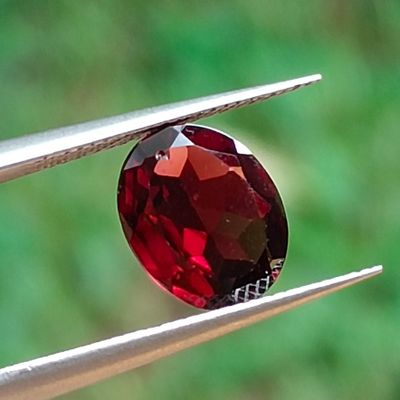 a close up of a red stone on a pair of pliers