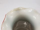 a white vase with a red rim sitting on a table