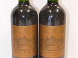 two bottles of red wine sitting next to each other on a white surface