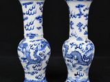 two blue and white vases with dragon designs on them on a black background