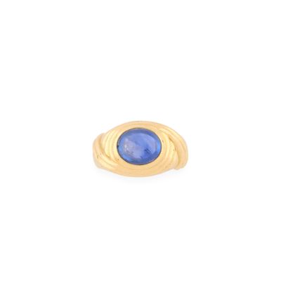 gros plan d'une bague en or avec une pierre bleue