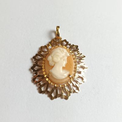 un gros plan d'un pendentif camée doré et blanc sur un fond blanc