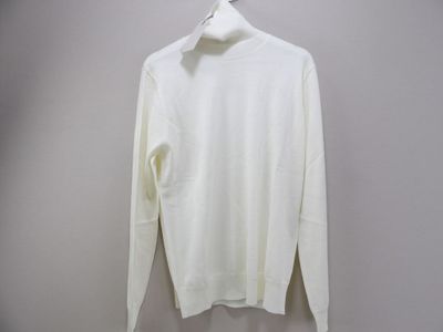 Le pull blanc est suspendu à un cintre accroché au mur.