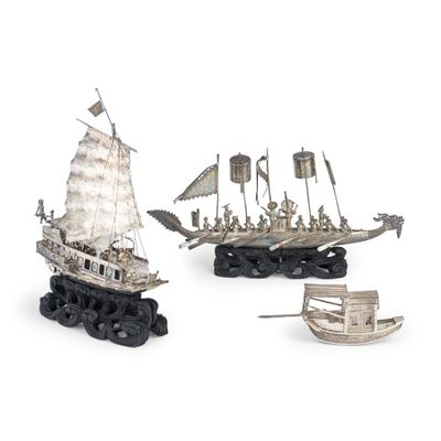 trois maquettes de bateaux en métal sont posées les unes à côté des autres sur une surface blanche