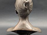 bronze bust of a woman with a bun on her head