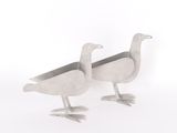 these are two metal birds standing next to each other on a white surface
