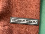 a close up of a brown flee jacket with the word step tech on it