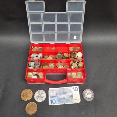 une boîte rouge remplie de nombreuses pièces et d'une grosse somme d'argent