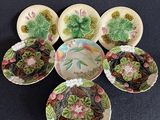 Plusieurs assiettes et bols sont disposés en cercle sur une surface noire.