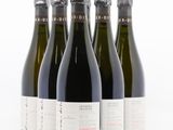 quatre bouteilles de vin sont alignées sur une surface blanche