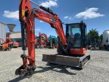 une photo montrant une pelleteuse rouge garée sur un parking