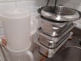 a kitchen sink with a bucket and pans on the counter