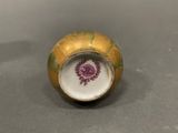 a yellow vase with a purple flower on it on a table