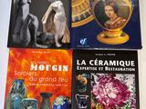 quatre livres posés sur une table sur laquelle se trouvent des vases et des tableaux
