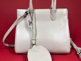 a white purse with a tag attached to it on a red background