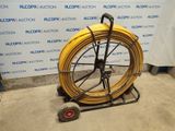 a yellow hose on a cart in front of a wall