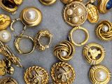 some gold rings and rings with pearls on a gray surface