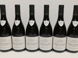 six bouteilles de vin sont alignées sur une table