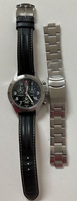 two watches sitting on a white surface next to each other