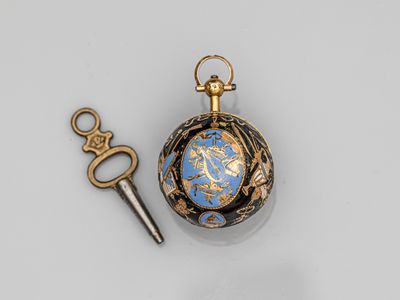 une montre de poche dorée et bleue et une clé posées sur une surface blanche