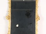 a gold frame with a black mirror on a white wall