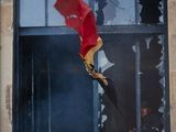 une fenêtre cassée à laquelle est suspendu un parapluie rouge
