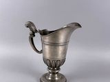 an antique silver plated pitcher on a pedestal with a handle