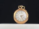 une montre de poche en or posée sur une boîte blanche