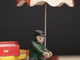 toy figurine of a man sitting on top of a red fire hydrant with an umbrella