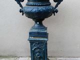 une urne bleue posée sur un socle sur le trottoir