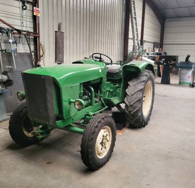 un tracteur vert garé à l'intérieur d'un bâtiment