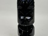 a black vase with a face on it on a white surface