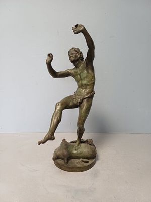 statue d'un homme assis sur un rocher, tenant une balle dans la main