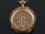 an old gold pocket watch with a chain on a black surface