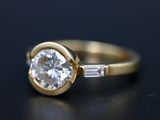 a close up of a gold ring with a diamond and baguets