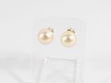 a pair of gold pearl earrings on a clear acrylic stand