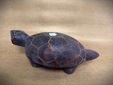 a small turtle figurine sitting on a brown surface