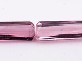 a close up of two pink glass beads on a white surface