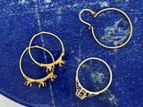trois paires de boucles d'oreilles créoles en or posées sur une pierre bleue