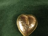 a gold heart shaped brooch on a green cloth