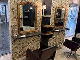 a photo of a hair salon with chairs and mirrors