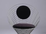 La chaise est en métal et est équipée d'un coussin noir.